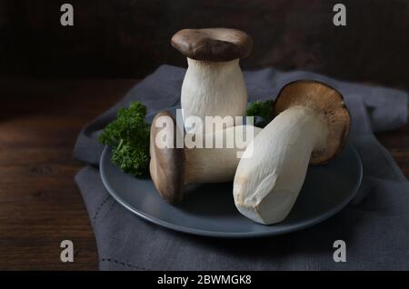 Les champignons des bois d'huîtres, Pleurotus eryngii, et le persil décorent sur une assiette bleue et une table en bois rustique foncé, espace de copie, foyer choisi Banque D'Images