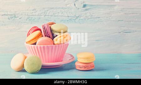 Macarons colorés dans une tasse sur un fond de bois bleu Banque D'Images