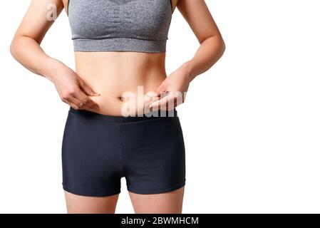 la femme appuie ses doigts sur les plis de graisse sur les côtés de son estomac. sur fond blanc Banque D'Images
