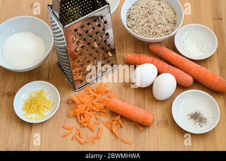 Carottes râpées, amandes moulues, œufs et épices, ingrédients à cuire sur un plan de cuisine en bois pour un gâteau de carottes de Pâques, concentration sélectionnée, profondeur étroite Banque D'Images