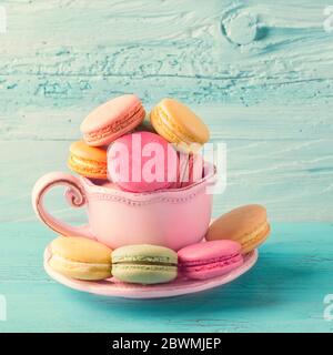 Macarons colorés dans une tasse sur un fond de bois bleu Banque D'Images