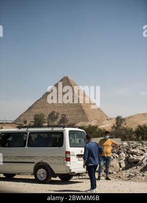 (200602) -- GIZA, 2 juin 2020 (Xinhua) -- On voit des personnes portant un masque facial dans une rue près des pyramides de Gizeh, à Gizeh, en Égypte, le 2 juin 2020. L'Égypte a signalé lundi 1,399 nouveaux cas de COVID-19, portant le nombre total dans le pays à 26,384. (Xinhua/Wu Huiwo) Banque D'Images