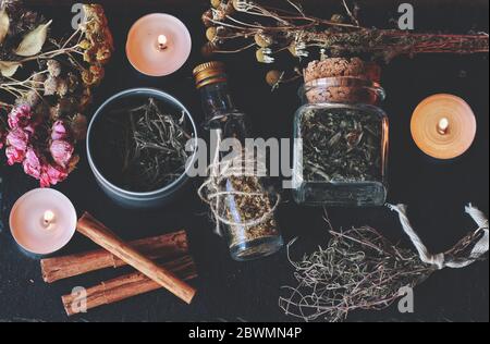 Plat de cuisine sorcellerie avec herbes et épices trouvés à la maison. Magick de fines herbes dans wicca et sorcellerie. Pots en verre remplis d'herbes séchées et d'épices Banque D'Images