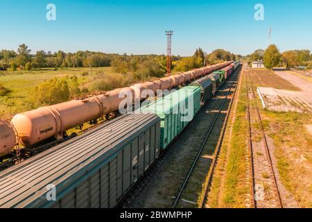 Wagons d'un train de cargaison en mouvement. Vue panoramique sur le train de marchandises mixtes dans le paysage rural. Banque D'Images