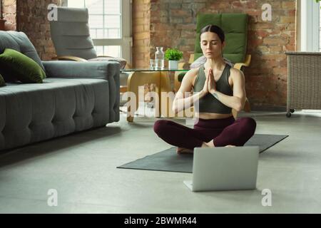 Équilibre. Jeune femme sportive de prendre des cours de yoga professionnels en ligne et de pratiquer à la maison. Concept de mode de vie sain, bien-être, bien-être, à la recherche de nouveaux passe-temps. Flexible et motivé. Banque D'Images