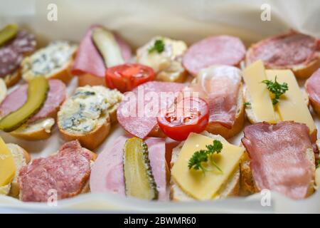 Plusieurs canapés de baguette au fromage et à la saucisse, tomates et cornichons servis sous forme de buffet décontracté, sélection de produits, champ étroit Banque D'Images