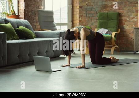 Équilibre. Jeune femme sportive de prendre des cours de yoga professionnels en ligne et de pratiquer à la maison. Concept de mode de vie sain, bien-être, bien-être, à la recherche de nouveaux passe-temps. Flexible et motivé. Banque D'Images