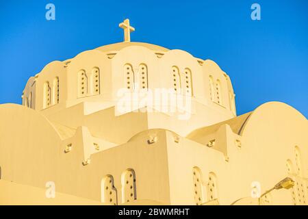 Détail de la cathédrale métropolitaine orthodoxe de Thira, sur l'île grecque de Santorin, au coucher du soleil créant une lueur jaune sur le bâtiment blanc Banque D'Images