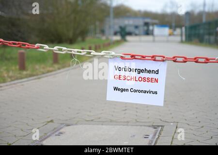 Barrière rouge de chaîne blanche devant une entreprise et signe avec texte allemand Vorübergehend geschlossen, wegen coronavirus, signifiant temporairement fermé dû Banque D'Images