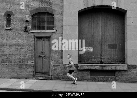 Coureur de sexe masculin avec toile de fond de l'entrepôt victorien délabré dans la rue de Londres en noir et blanc Banque D'Images