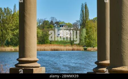 Vue à travers des colonnes de pierre sur un lac avec une bande de roseaux à une ancienne villa dans un parc Banque D'Images