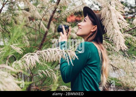 Jeune femme élégante prenant des photos à l'aide d'un appareil photo compact dans un jardin d'été. Fille appréciant le passe-temps dans le parc Banque D'Images