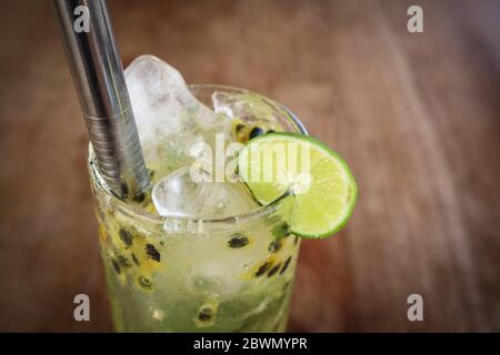 Cocktail mojito de fruits de la passion avec paille de métal sur table en bois dans le café de gros plan Banque D'Images