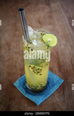 Cocktail de mojito de fruits de la passion avec paille de métal sur table en bois dans le café. Banque D'Images