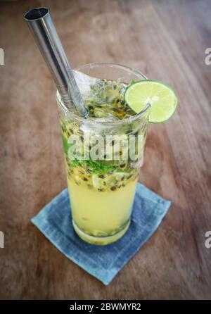 Cocktail de mojito de fruits de la passion avec paille de métal sur table en bois dans le café. Banque D'Images
