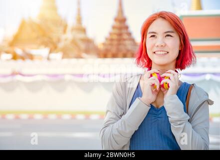Portrait Thai asiatique fille nouvelle génération jeune pop teen teen teint rouge cheveux couleur ombre sourire avec Thaïlande temple arrière-plan. Banque D'Images