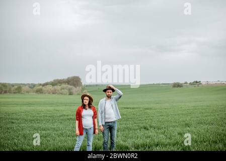 Portrait d'un couple charmant debout ensemble sur le terrain vert. Couple heureux s'attendant à un bébé, jeune concept de famille Banque D'Images
