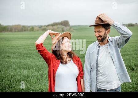 Portrait d'un couple charmant debout ensemble sur le terrain vert. Couple heureux s'attendant à un bébé, jeune concept de famille