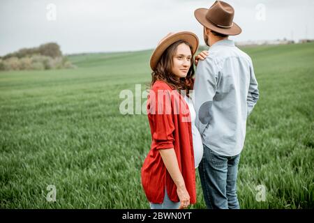 Portrait d'un couple charmant debout ensemble sur le terrain vert. Couple heureux s'attendant à un bébé, jeune concept de famille Banque D'Images