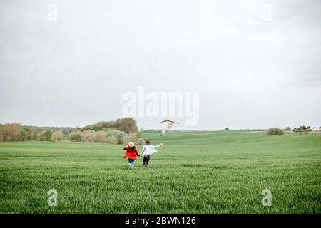Couple heureux s'amuser ensemble, jouer avec le cerf-volant sur le terrain de verdure. Un couple heureux attend un concept de famille de bébé et de jeune Banque D'Images