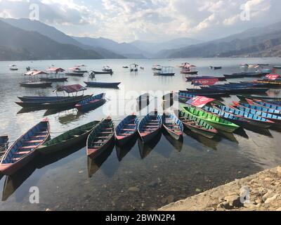 Canoës colorés sur le lac avec montagnes, Pokhara Népal Banque D'Images