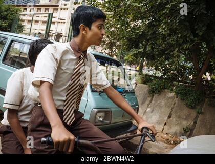 Deux garçons en uniforme d'école marron et crème sont passés à vélo à Bangaluru, Karnataka, Inde. Banque D'Images