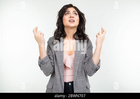 une fille dans une veste classique grise à carreaux prie sur un fond blanc Banque D'Images