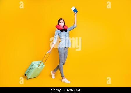 Profil pleine longueur côté photo étudiant fille tenir des billets sac bagages voyage à l'étranger aller enregistrement porter masque médical doux cou coussin Jean chemise Banque D'Images