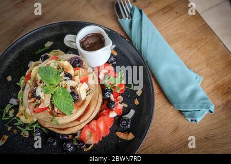 Crêpes avec banane, bleuets, fraises et sauce au chocolat sur une assiette vue du dessus Banque D'Images