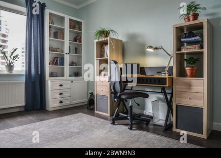 Chambre pour adolescents lumineuse et confortable avec bibliothèques blanches, bureau et ordinateur portable Banque D'Images