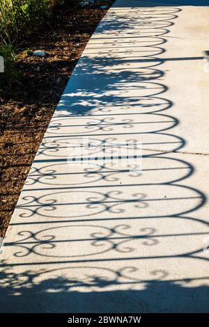 Une clôture en fer projette des ombres sur le trottoir; au cœur du jardin de guérison du centre médical régional des Rocheuses; Salida; Colorado; États-Unis Banque D'Images