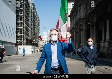 Un homme portant un drapeau italien est vu porter un masque aux mêmes couleurs.la Ligue (Lega), les Frères d'Italie (Fratelli d'Italia) et Forza Italia se sont rassemblés sur la place du Dôme à Milan, pour célébrer le jour de la République (Festa della Repubblica). À la lumière de l'urgence Covid-19, les gens ont respecté les distances sociales tout en célébrant et en protestant les mesures du gouvernement national. Les mouvements de gauche se sont opposés à la célébration. Banque D'Images