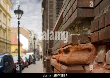 Briques cassées dans le mur de la vieille maison sur la rue de la ville européenne Banque D'Images