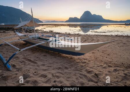 Coucher de soleil tropical coloré avec un bateau banca local à El Nido, Palawan - Philippines Banque D'Images