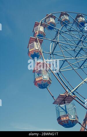 Vue en angle bas d'une excursion d'époque dans le parc des expositions Ferris Wheel avec sièges enfermé sous un ciel bleu et une composition verticale Banque D'Images