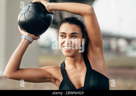 Femme souriante dans des vêtements de sport faisant de l'entraînement de fitness à l'aide d'un medecine ball Banque D'Images