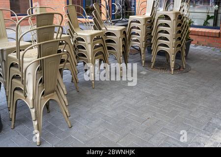 Chaises empilées dans un café de rue qui n'est pas autorisé à ouvrir en raison de la crise du coronavirus, catastrophe économique pour la gastronomie et des affaires similaires, Banque D'Images