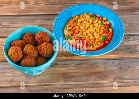 Boulettes de falafel dans un plat et un houmous, pois chiches, tahini à l'huile d'olive, poivre, épices dans une assiette sur table en bois. Alimentation végétalienne traditionnelle du Moyen-Orient. Banque D'Images