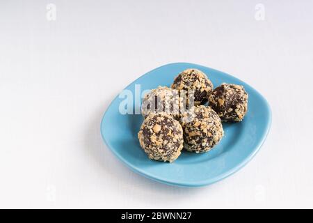 Cinq boules d'énergie faites maison sur une assiette bleue. Un dessert au chocolat maison sain pour le petit déjeuner vous remplira d'énergie. Arrosés d'écrous Banque D'Images