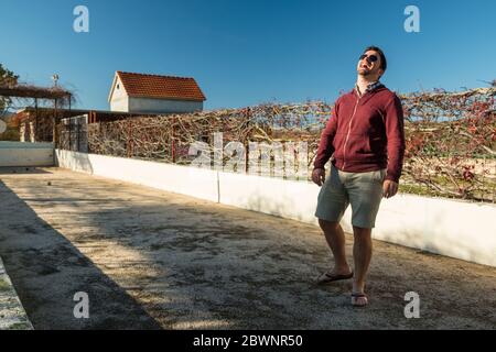 Un jeune homme portant des lunettes de soleil rit tout en faisant du bowling sur une pelouse en plein air à Dalmatie, en Croatie Banque D'Images