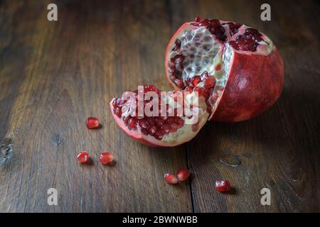 Fruits grenade ouverts avec graines juteuses rouges sur bois rustique foncé, espace de copie Banque D'Images
