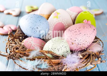 Oeufs de pâques colorés biscuits et oeufs de pâques dans un nid en bois sur fond bleu en bois, gros plan Banque D'Images
