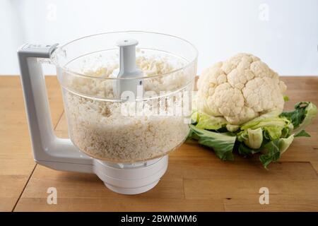 chou-fleur déchiqueté dans un robot de cuisine pour une croûte de pizza saine à faible teneur en carb ou comme remplacement de riz végétal sur une table de cuisine en bois, foyer choisi, Banque D'Images