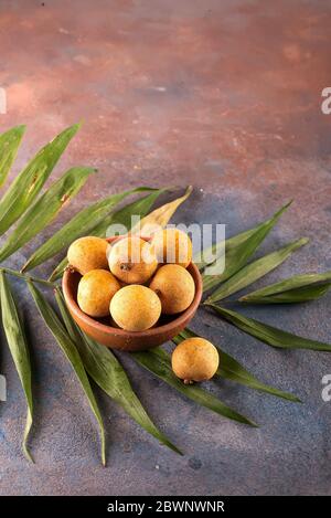 Longan aux fruits tropicaux dans le panier de bambou sur fond de pierre Banque D'Images