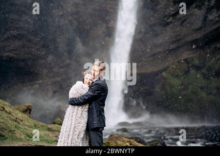 Destination mariage Islande, près de la cascade de Kvernufoss. Le couple de mariage est debout près de la cascade. Le marié encadre la mariée. Banque D'Images