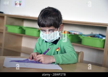 Ankara, Turquie. 2 juin 2020. Un garçon portant un masque dessine une image à un jardin d'enfants rouvert à Ankara, Turquie, le 2 juin 2020. La pandémie de COVID-19 en Turquie a continué de ralentir mardi, avec 786 nouveaux cas d'infection enregistrés, portant le nombre total de cas confirmés à 165,555. Crédit: Mustafa Kaya/Xinhua/Alamy Live News Banque D'Images