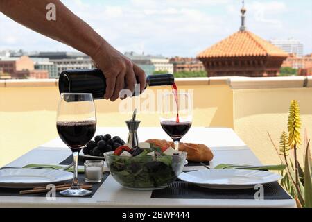 Vin rouge versé à la main préparer le repas du midi en terrasse Banque D'Images