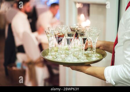 Plateau de transport pour serveur avec plusieurs boissons alcoolisées. Homme servant des boissons. Célébration, anniversaire, fête, mariage. Banque D'Images