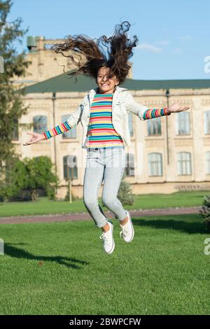 joyeux enfant sautant haut. sens de la liberté. bonheur d'enfance. petite fille avec des cheveux bouclés saut à l'extérieur. vacances de printemps enfin. enfant célébrant le succès. ajoutez du mouvement à votre vie. Banque D'Images