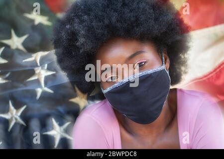 Un portrait d'une belle fille noire portant des masques avec le drapeau des États-Unis sur le fond. Banque D'Images